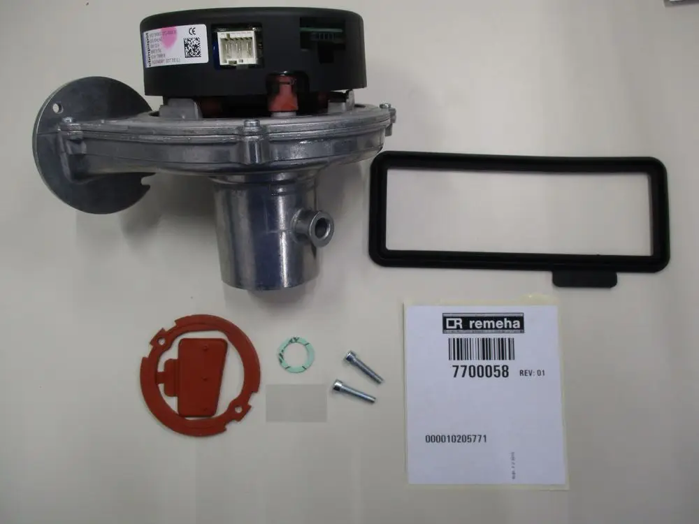 Ventilator von Remeha mit montiertem Gehäuse, Dichtungen und Schrauben. Zubehörteile wie Gummiring, Scheibe und abnehmbarer Deckel sind ebenfalls sichtbar.